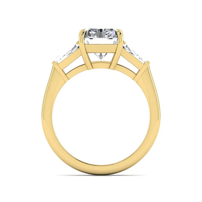 Radiant cut lab grown diamond three stone engagement ring with tapered baguette side diamonds and four prong setting in yellow gold tone.