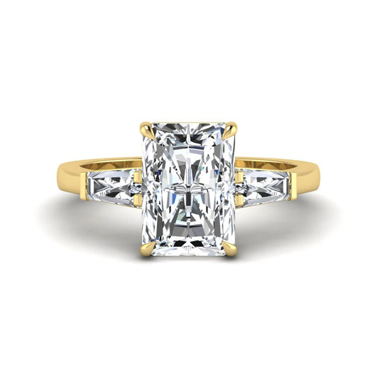 Radiant cut lab grown diamond three stone engagement ring with tapered baguette side diamonds and four prong setting in yellow gold tone.