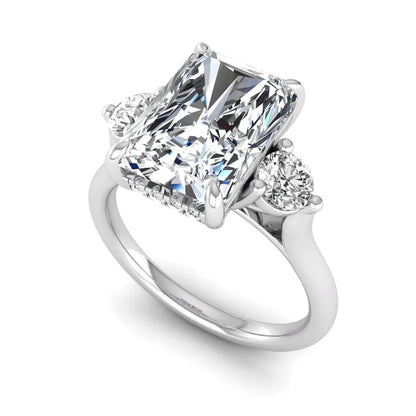 Radiant cut lab grown diamond three stone engagement ring with round side diamonds in a four-prong setting and white gold tone band.