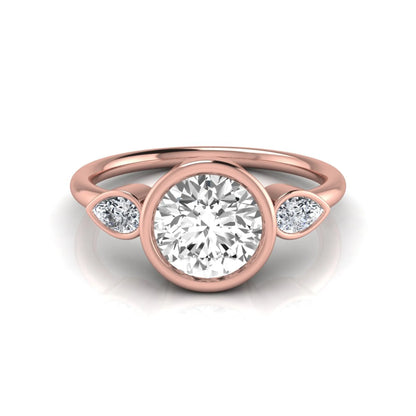 Round cut lab grown diamond bezel three stone engagement ring featuring a 1.28 carat IGI certified center diamond with pear cut side diamonds in rose gold.