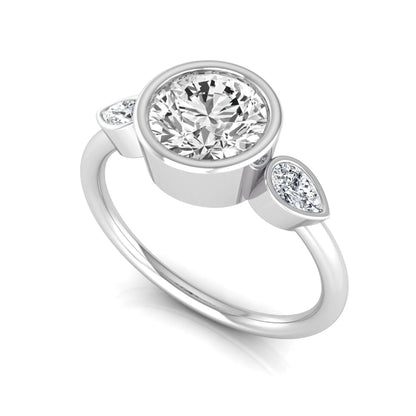 Round cut lab grown diamond bezel three stone engagement ring featuring a 1.28 carat IGI certified center diamond with pear cut side diamonds in white gold.