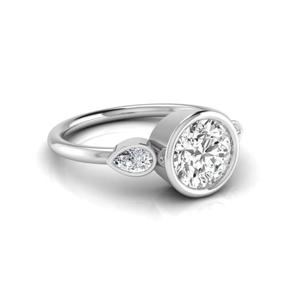 Round cut lab grown diamond bezel three stone engagement ring featuring a 1.28 carat IGI certified center diamond with pear cut side diamonds in white gold.