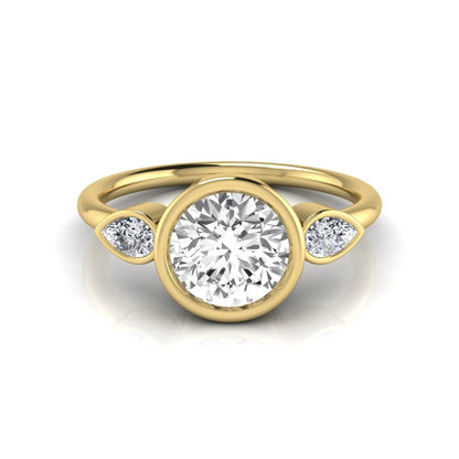Round cut lab grown diamond bezel three stone engagement ring featuring a 1.28 carat IGI certified center diamond with pear cut side diamonds in yellow gold.