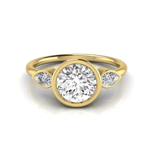 Round cut lab grown diamond bezel three stone engagement ring featuring a 1.28 carat IGI certified center diamond with pear cut side diamonds in yellow gold.