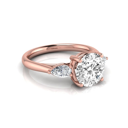 Round cut lab grown diamond three stone engagement ring featuring a 2.04 carat IGI certified center diamond with pear side diamonds in rose gold