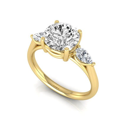 Round cut lab grown diamond three stone engagement ring featuring a 2.04 carat IGI certified center diamond with pear side diamonds in yellow gold