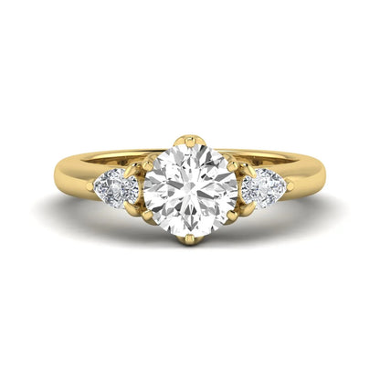 Round cut lab grown diamond three stone engagement ring with pear side diamonds in yellow gold.