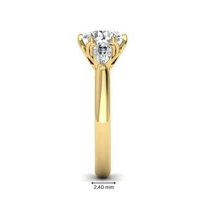 Round cut lab grown diamond three stone engagement ring with pear side diamonds in yellow gold.