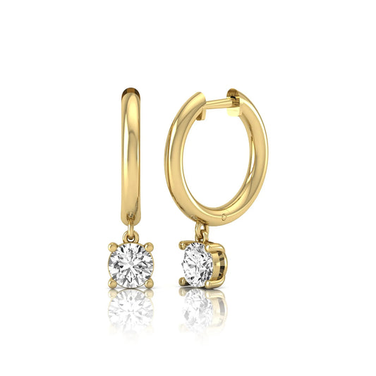 Round cut lab grown diamond drop huggie hoop earrings featuring a four prong drop setting, hinged snap closure, and polished yellow gold tone finish.