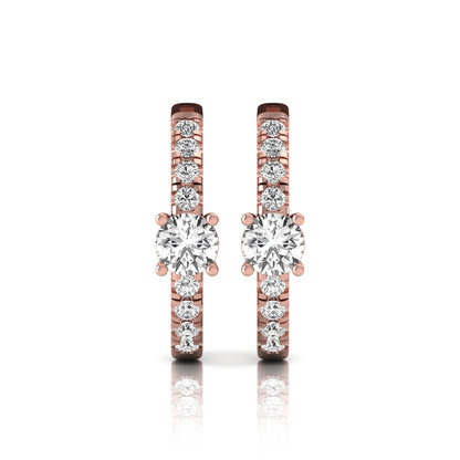 Round brilliant lab grown diamond pavé huggie hoop earrings featuring a four prong center diamond with graduated shared prong pavé round diamonds in rose gold.