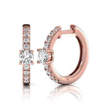 Round brilliant lab grown diamond pavé huggie hoop earrings featuring a four prong center diamond with graduated shared prong pavé round diamonds in rose gold.