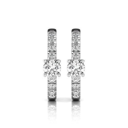 Round brilliant lab grown diamond pavé huggie hoop earrings featuring a four prong center diamond with graduated shared prong pavé round diamonds in white gold.