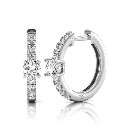 Round brilliant lab grown diamond pavé huggie hoop earrings featuring a four prong center diamond with graduated shared prong pavé round diamonds in white gold.