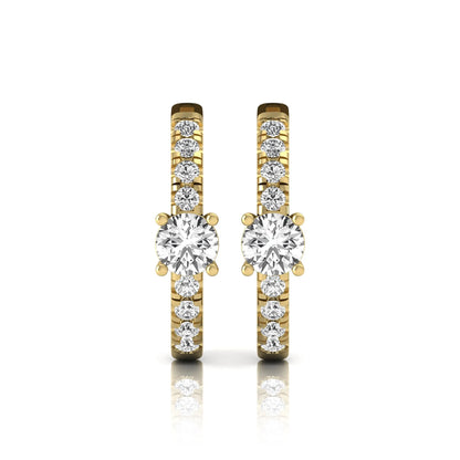 Round brilliant lab grown diamond pavé huggie hoop earrings featuring a four prong center diamond with graduated shared prong pavé round diamonds in yellow gold.