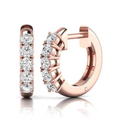 Round cut lab grown diamond front-facing huggie hoop earrings featuring a shared four prong setting, hinged snap closure, and polished rose gold finish.