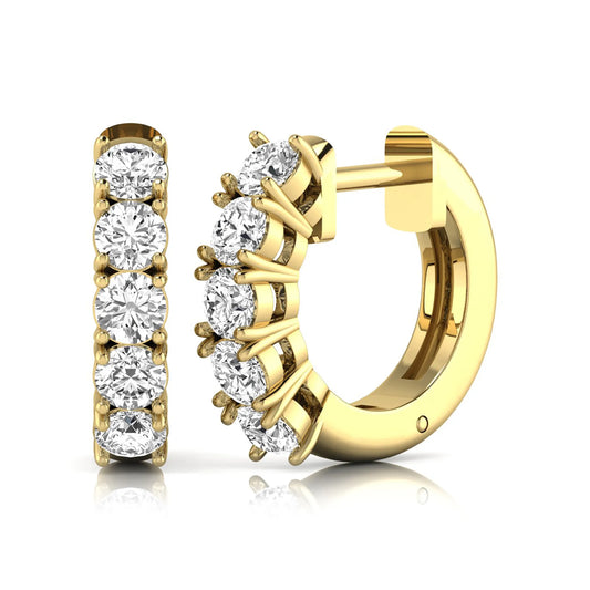 Round cut lab grown diamond huggie hoop earrings featuring five front-facing diamonds in a shared four prong setting with a hinged snap closure and polished yellow gold finish.