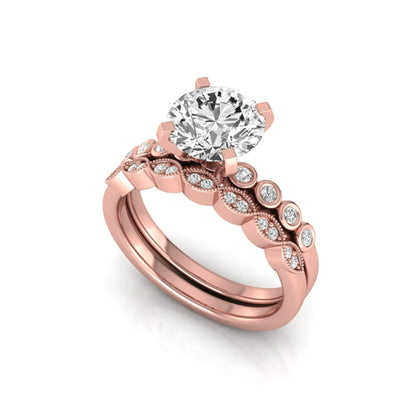 Round cut lab grown diamond bridal ring set featuring a four-prong solitaire engagement ring with a matching side stone wedding band accented by round bezel-set diamonds and vintage milgrain detailing in rose gold
