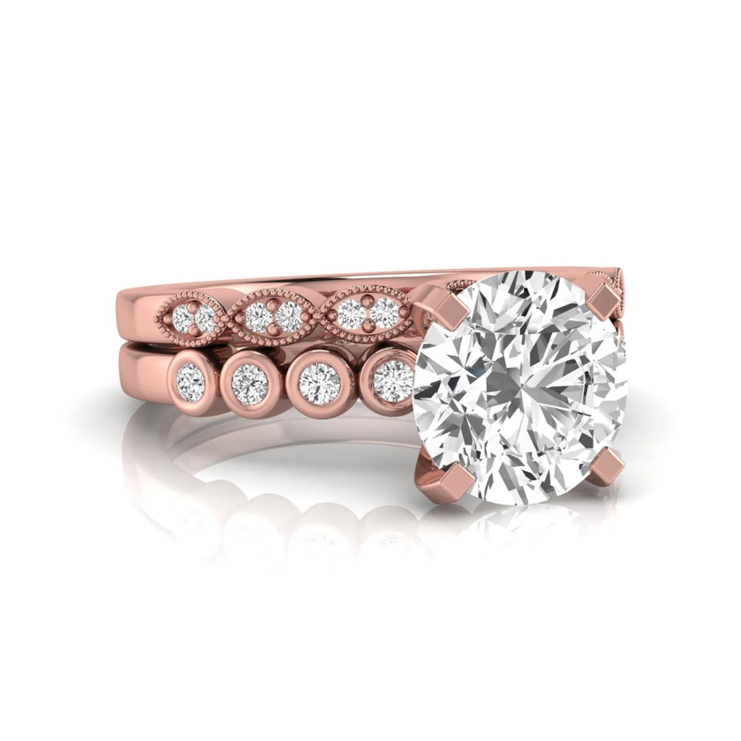 Round cut lab grown diamond bridal ring set featuring a four-prong solitaire engagement ring with a matching side stone wedding band accented by round bezel-set diamonds and vintage milgrain detailing in rose gold