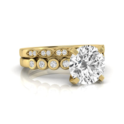 Round cut lab grown diamond bridal ring set featuring a four-prong solitaire engagement ring with a matching side stone wedding band accented by round bezel-set diamonds and vintage milgrain detailing in yellow gold