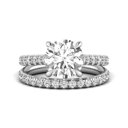 Round cut lab grown diamond bridal ring set featuring a four-prong solitaire center diamond with pavé-set engagement ring and matching pavé wedding band in a white gold finish.