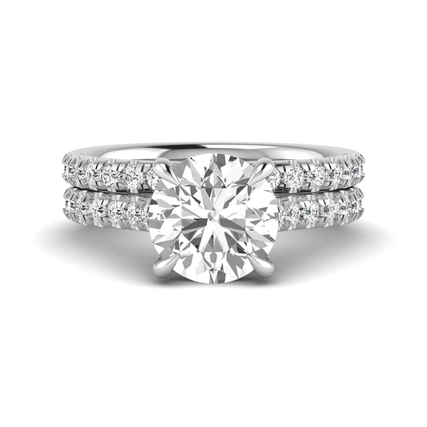 Round cut lab grown diamond bridal ring set featuring a four-prong solitaire center diamond with pavé-set engagement ring and matching pavé wedding band in a white gold finish.