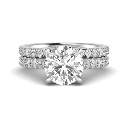 Round cut lab grown diamond bridal ring set featuring a four-prong solitaire center diamond with pavé-set engagement ring and matching pavé wedding band in a white gold finish.