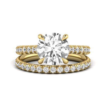 Round cut lab grown diamond bridal ring set featuring a four-prong solitaire center diamond with pavé-set engagement ring and matching pavé wedding band in a yellow gold finish.