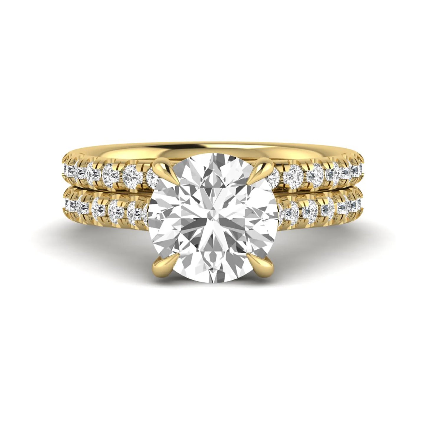 Round cut lab grown diamond bridal ring set featuring a four-prong solitaire center diamond with pavé-set engagement ring and matching pavé wedding band in a yellow gold finish.