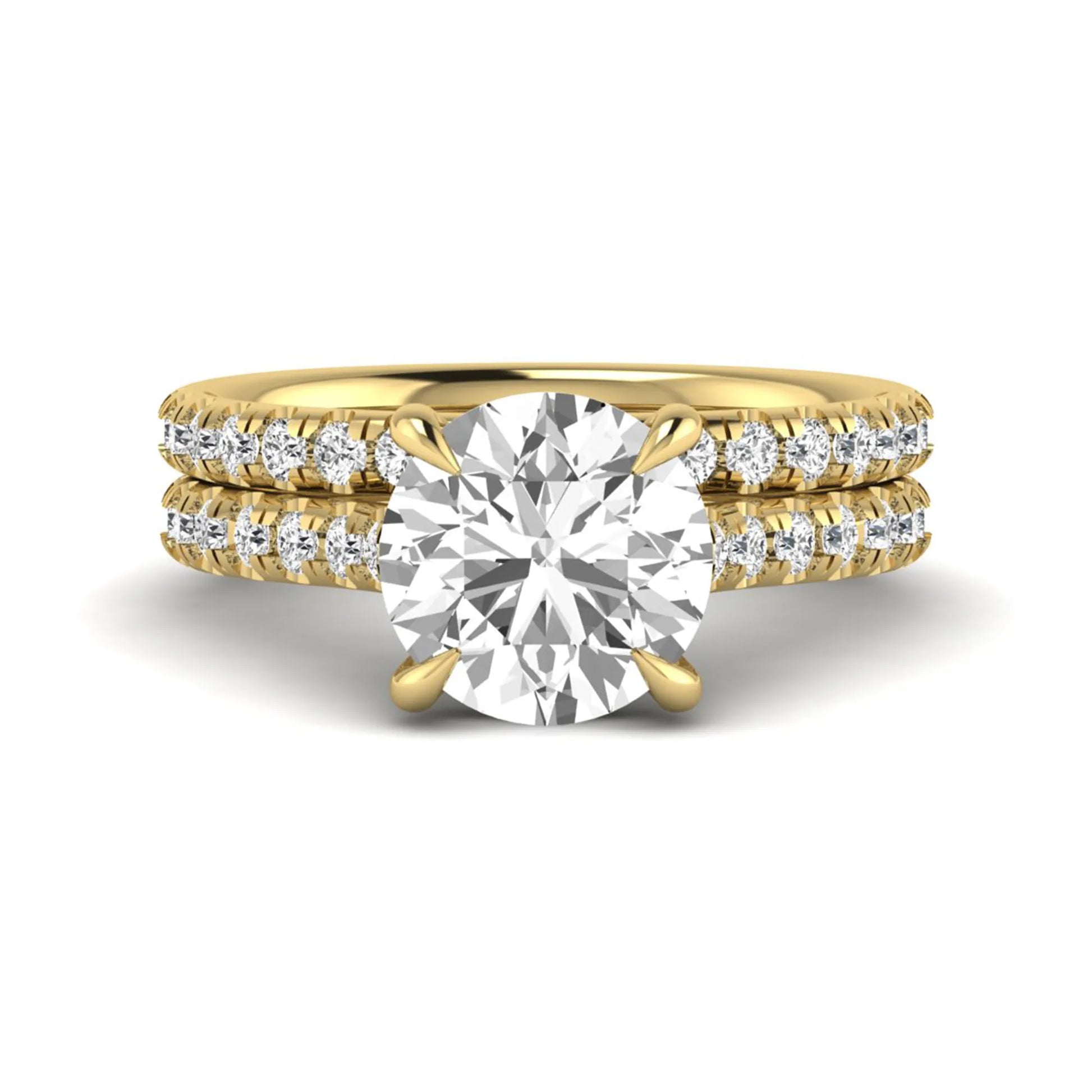 Round cut lab grown diamond bridal ring set featuring a four-prong solitaire center diamond with pavé-set engagement ring and matching pavé wedding band in a yellow gold finish.