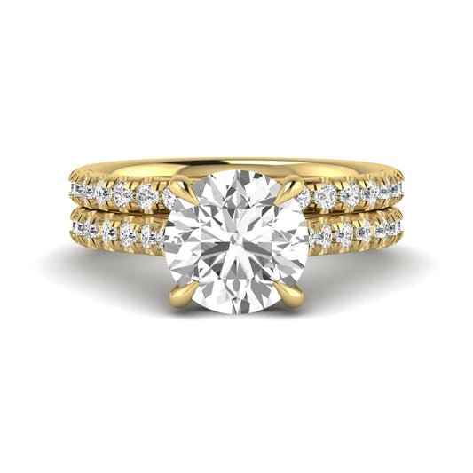 Round cut lab grown diamond bridal ring set featuring a four-prong solitaire center diamond with pavé-set engagement ring and matching pavé wedding band in a yellow gold finish.