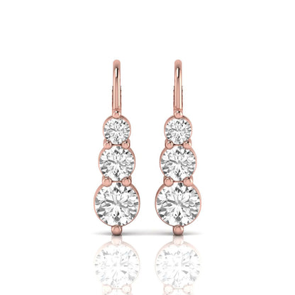 Round cut lab grown diamond graduated three stone drop earrings featuring a shared four-prong setting with secure lever back closure and rose gold tone design.