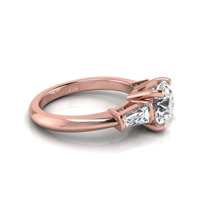 Round cut lab grown diamond three-stone engagement ring featuring tapered baguette side diamonds in a classic four-prong rose gold setting.