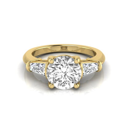 Round cut lab grown diamond three-stone engagement ring featuring tapered baguette side diamonds in a classic four-prong yellow gold setting.