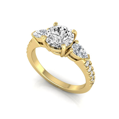 Round cut lab grown diamond three stone engagement ring featuring a 1.28 carat IGI certified center diamond with pear and round side diamonds on a pavé yellow gold band.