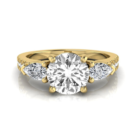 Round cut lab grown diamond three stone engagement ring featuring a 1.28 carat IGI certified center diamond with pear and round side diamonds on a pavé yellow gold band.