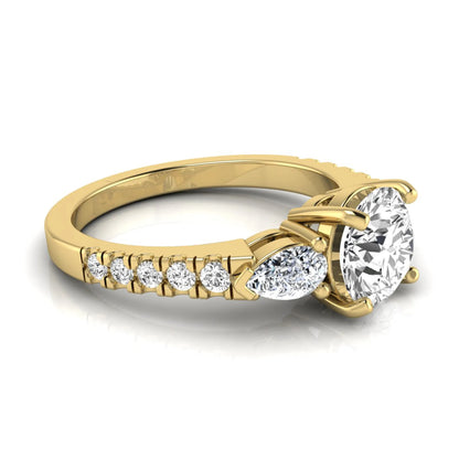 Round cut lab grown diamond three stone engagement ring featuring a 1.28 carat IGI certified center diamond with pear and round side diamonds on a pavé yellow gold band.