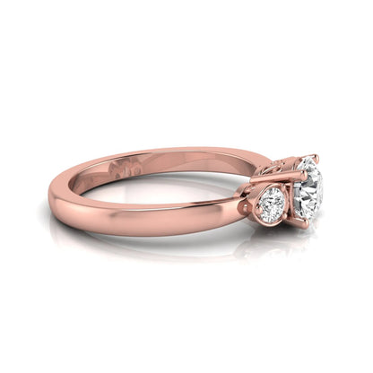 Round cut lab grown diamond three stone engagement ring featuring a brilliant center diamond with round side diamonds in a four-prong rose gold tone setting.