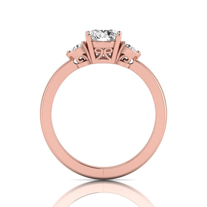Round cut lab grown diamond three stone engagement ring featuring a brilliant center diamond with round side diamonds in a four-prong rose gold tone setting.
