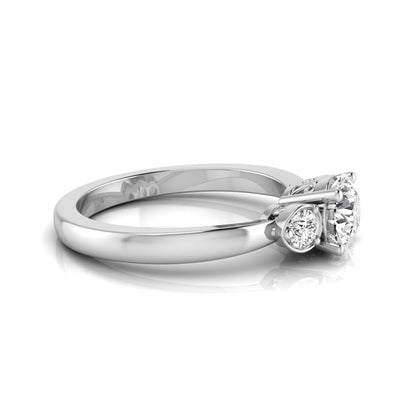 Round cut lab grown diamond three stone engagement ring featuring a brilliant center diamond with round side diamonds in a four-prong white gold tone setting.