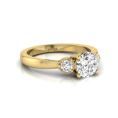 Round cut lab grown diamond three stone engagement ring featuring a brilliant center diamond with round side diamonds in a four-prong yellow gold tone setting.