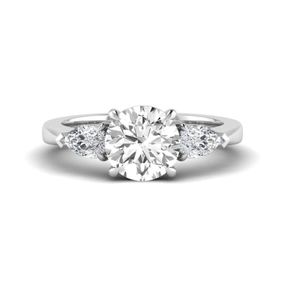 Round three stone prong set lab grown diamond engagement ring featuring a 2.00 carat round center diamond with pear cut side diamonds in white gold finish.