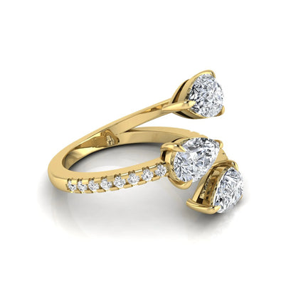 Three stone pear cut lab grown diamond wrap ring featuring round diamond accents and pavé shoulders in polished yellow gold.